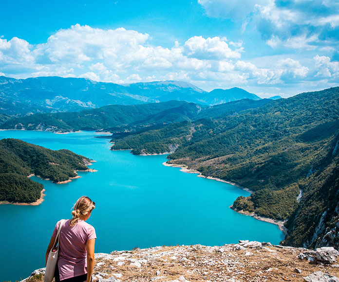 Mujer haciendo turismo de vacaciones observando el Lago Bovilla, Albania, desde las alturas