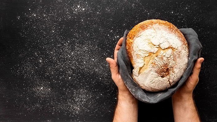 manos enseñando un pan artesano sobre un paño negro