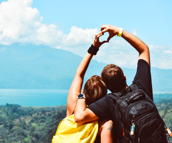 Pareja de viaje y formando un corazón con sus manos.