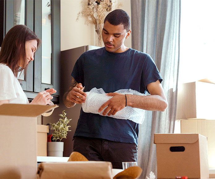 Pareja empaquetando enseres en cajas de cartón.