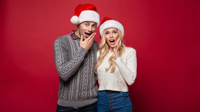 pareja con gorros de Navidad y cara de sorprendidos