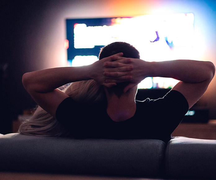 Pareja recostados en el sofá viendo la television