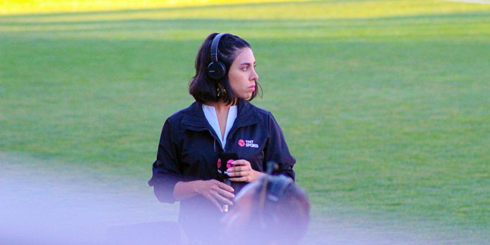 Periodista comentarista deportivo con micrófono esperando para retransmitir un partido de fútbol