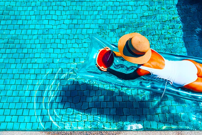 Mujer relajada comiendo sandía en una piscina