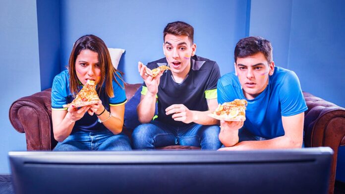 amigos viendo la televisión mientras comen pizza