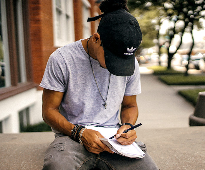Hombre joven sentado en la calle escribiendo