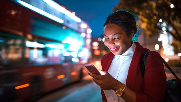 chica sonriendo mirando la pantalla de un teléfono móvil