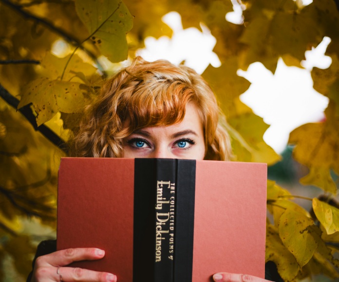 Mujer asomándose sobre un libro.