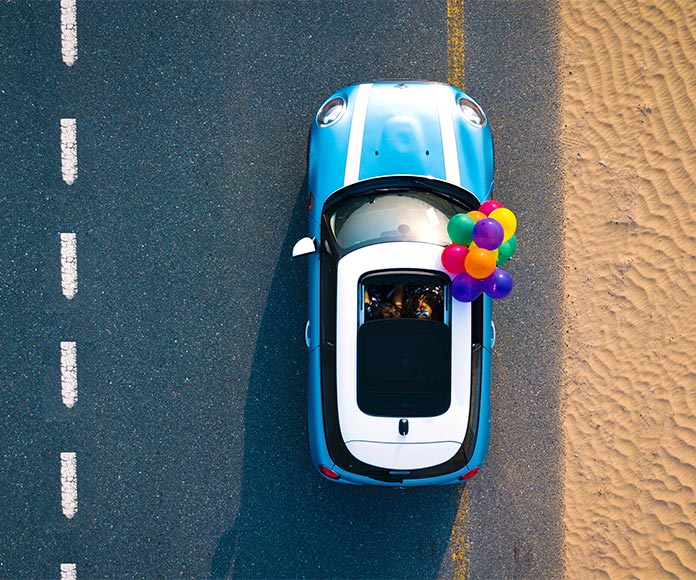 Vista cenital de un coche azul con globos de colores