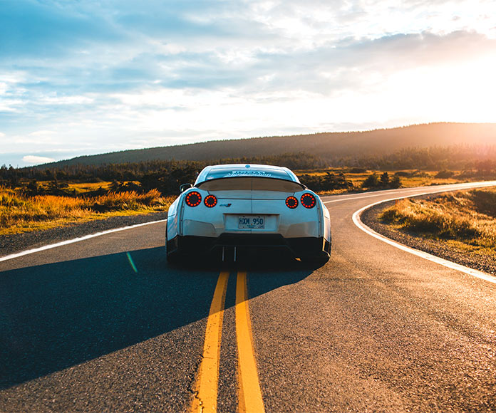 Coche deportivo en una carretera al atardecer