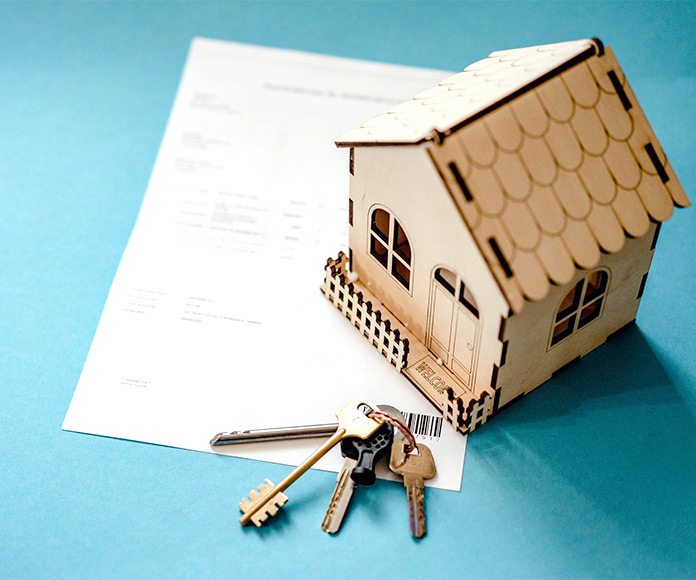 Llaves y casita de cartón sobre papeles hipotecarios