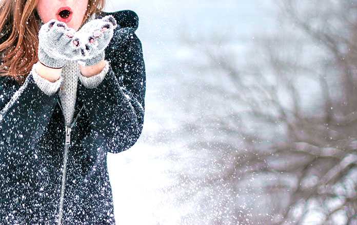 Mujer abrigada jugando con la nieve