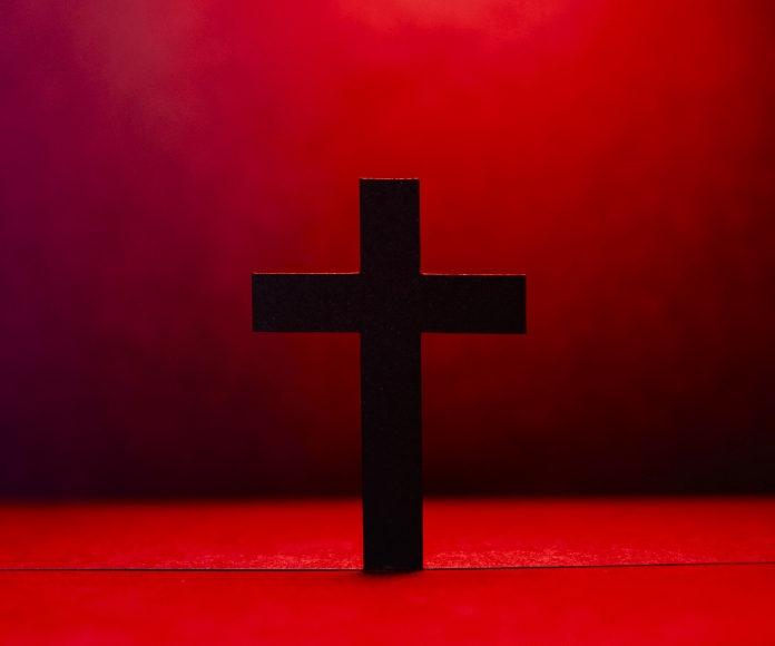 Cruz latina delante de un escenario rojo.