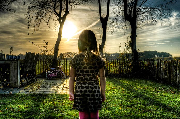 Niña mirando de frente al sol