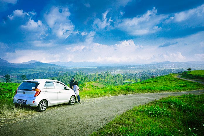 personas viendo el paisaje sentadas sobre el capó del coche