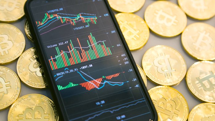 Teléfono móvil con gráficas de inversiones economicas en bolsa con Bitcoins por detrás