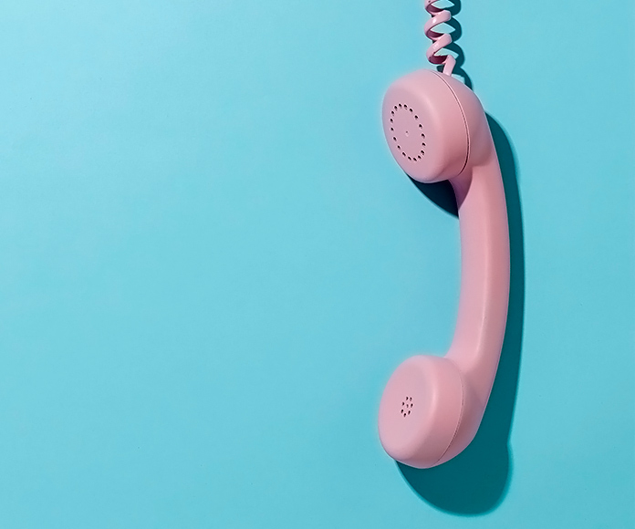 Teléfono vintage rosado sobre fondo azul