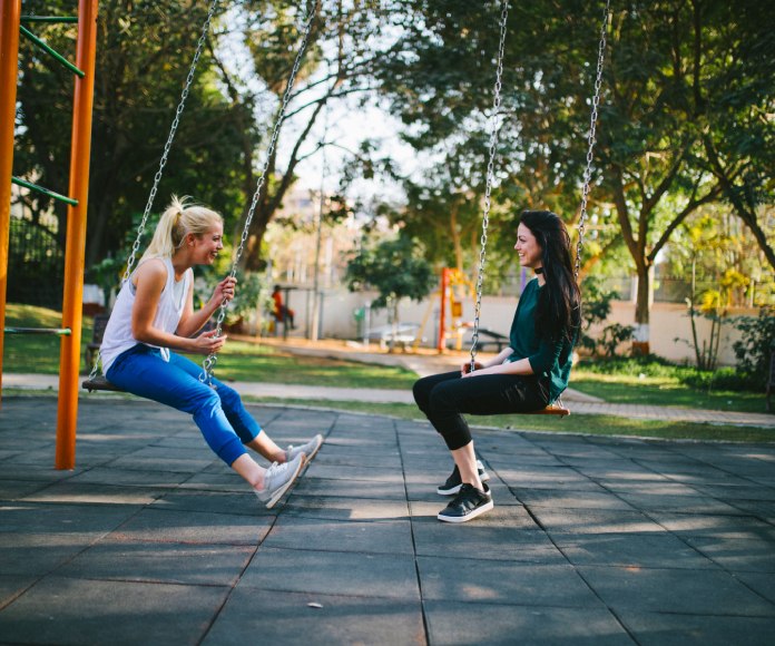 Dos chicas hablando en un columpio.