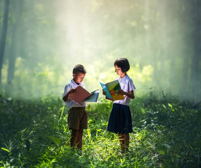 Dos niños leyendo en el bosque.