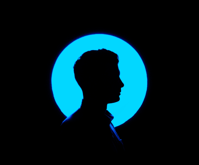 Hombre posando de perfil con una luz azul.