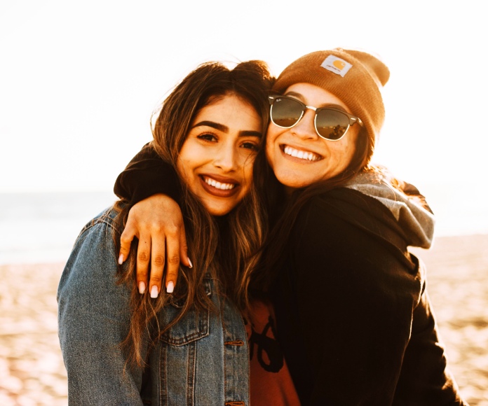 Amigas abrazándose en un clima soleado.