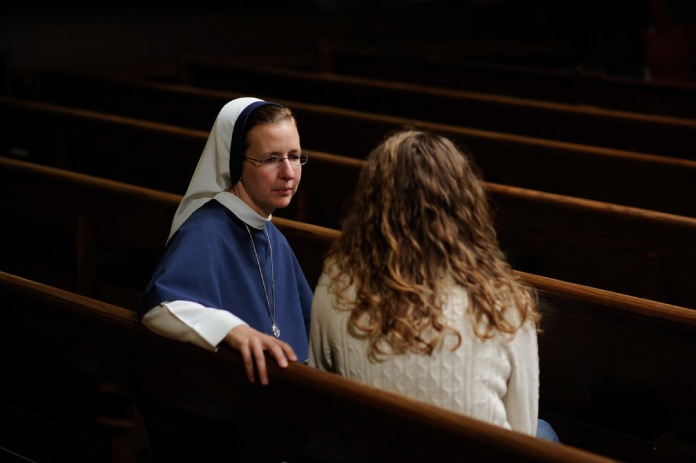 Monja cristiana conversando con una mujer.