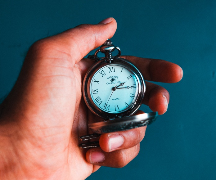 Persona sosteniendo un reloj de bolsillo.