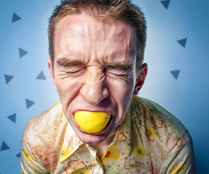 Hombre con limón en la boca y ojos cerrados
