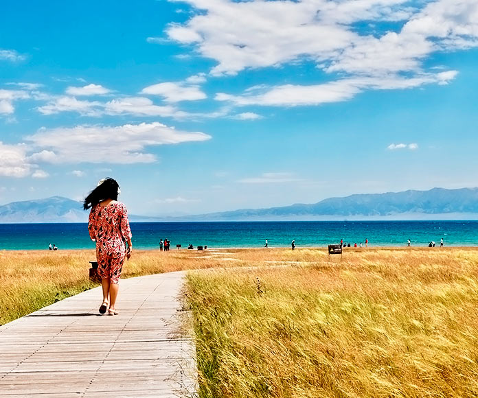 Mujer caminando por un paseo de madera en una playa de Europa