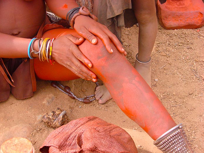 Mujer himba cubriéndose con el ungüento rojo