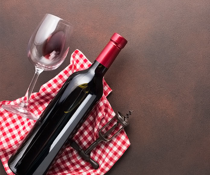 Botella y copa de vino sobre un mantel encima de una mesa