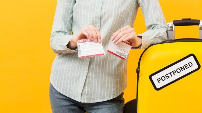 mujer rompiendo un billete de avión junto a una maleta con una pegatina que dice 